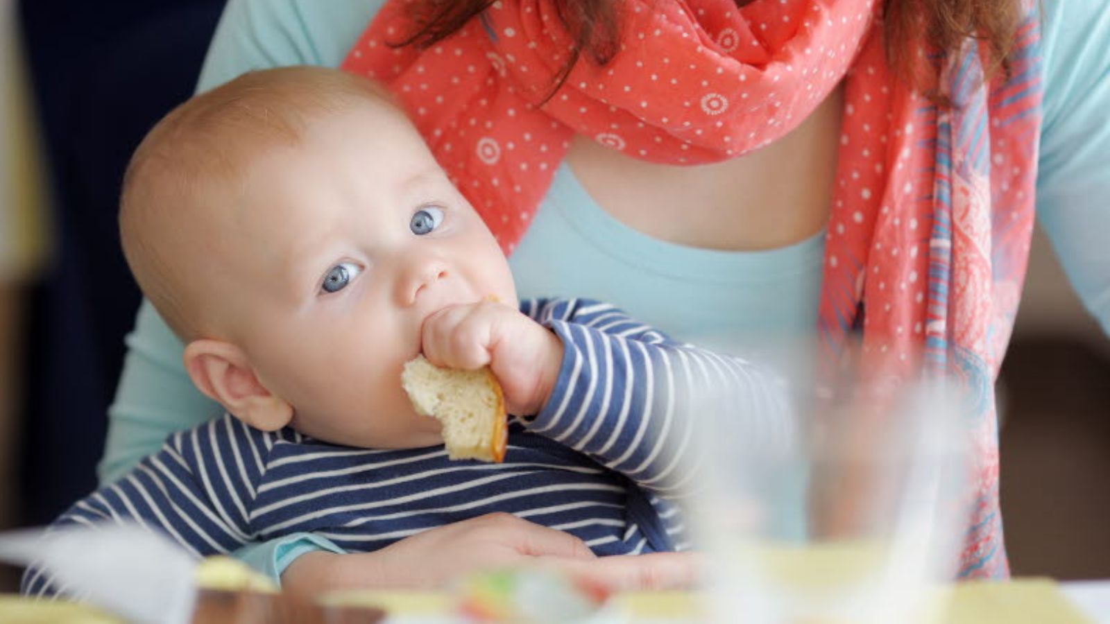 Barn som äter macka i sin mammas knä